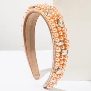 Détail macro de perles champagne et strass marquise sur un serre-tête en velours