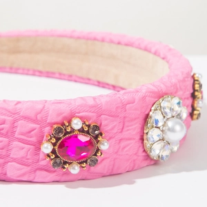 Detailed macro view of pink satin headband with elegant pearls and rose red gemstones