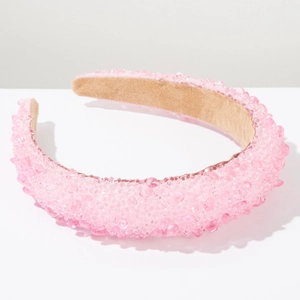 Macro detail of a pink beaded padded headband with crystal resin stones on white background