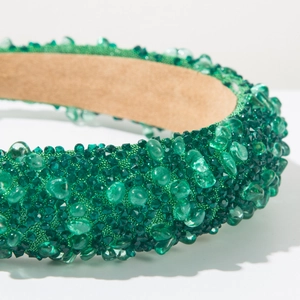 Close-up of emerald green baroque headband with sparkling crystals and padded fabric
