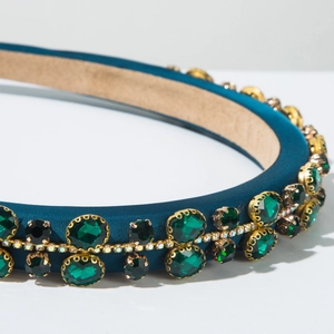 Detailed close-up of a blue satin headband featuring emerald crystals and rainbow rhinestones
