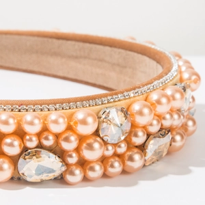 Détail d'un serre-tête en velours avec strass brillants et perles sur tissu champagne