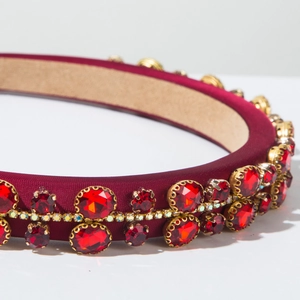 Detailed close-up of velvet headband with large red gemstones and shimmering crystals