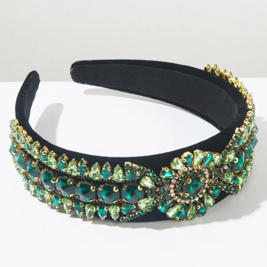 Detailed view of luxury baroque headband with green crystals on black velvet
