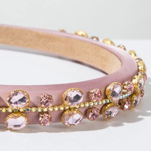 Detail of pink satin headband featuring crystal rhinestones and golden claw setting