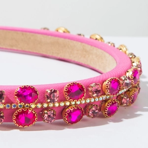 Close-up of pink luxury padded headband with sparkling gemstones and gold claw settings