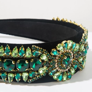 Detail of baroque headband with green crystals and floral rhinestones on black velvet