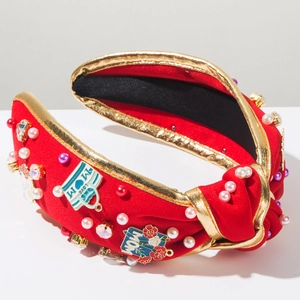 Detail of red knotted headband with gold trim, MOM and LOVE charms and faux pearls