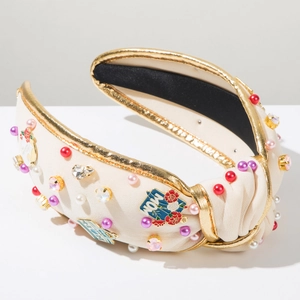Detailed shot of cream MOM headband with colorful pearls and rhinestones on fabric