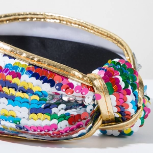 Close-up of rainbow sequin headband featuring a twisted design and golden braided edges
