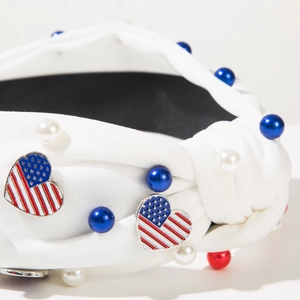 Détail macro d'un serre-tête blanc noué avec motifs cœurs drapeau USA et perles