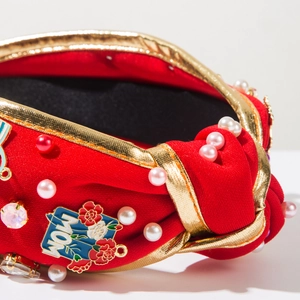 Close-up of red fabric headband with MOM pendant, pearls, and rhinestones