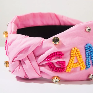 Vue détaillée du bandeau en tissu rose avec des perles colorées et des strass brillants