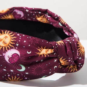 Macro shot of knot detail on burgundy velvet headband with celestial sun and moon prints