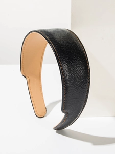 Détail d'un serre-tête en cuir noir avec surpiqûres orange sur un support blanc
