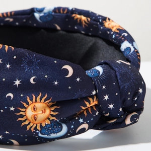 Detailed close-up of dark blue knotted headband with gold sun and moon fabric prints