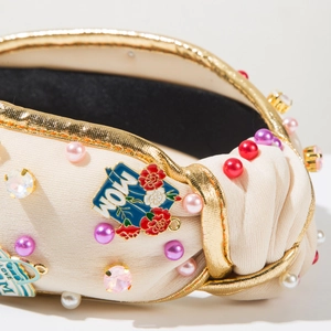 Macro detail of MOM pearl headband with colorful crystals and blue floral enamel charm
