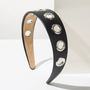 Détail d'un serre-tête en cuir noir avec de grands œillets métalliques argentés punk