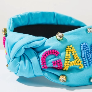 Détail de la broderie de perles colorées et strass sur le bandeau noué en tissu bleu