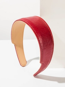 Gros plan du serre-tête en cuir synthétique rouge avec texture grainée et coutures jaunes
