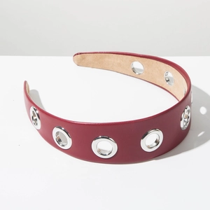 Détail d'un serre-tête en cuir bordeaux avec œillets métalliques et doublure en velours