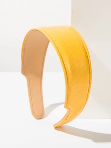 Gros plan du serre-tête large en cuir jaune vif avec texture plissée et couture
