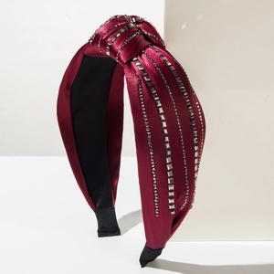 Close-up of wine red satin knotted headband with square rhinestones on display