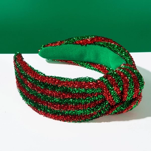 Gros plan d'un serre-tête de Noël rayé rouge et vert avec paillettes et nœud brillant