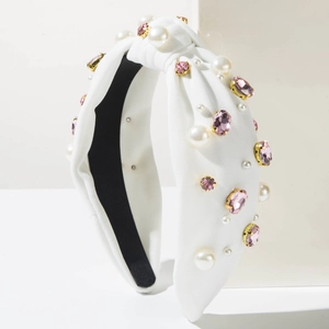 Détail du serre-tête noué large avec perles blanches et cristaux roses sur tissu blanc