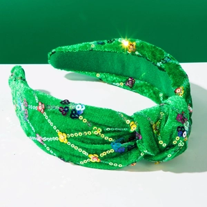 Détail d'un serre-tête en velours vert noué avec des motifs floraux en paillettes colorées