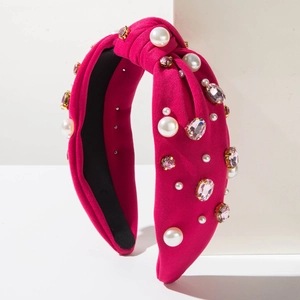 Détail d'un serre-tête noué fuchsia avec perles blanches et strass roses sur tricot