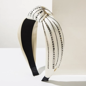 Detail of cream knotted headband with rows of grey rhinestones on satin fabric