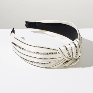 Close-up of white satin knotted headband with sparkling rhinestones and metal studs