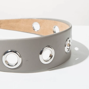 Détail d'un serre-tête en cuir gris avec de grands œillets métalliques argentés et doublure