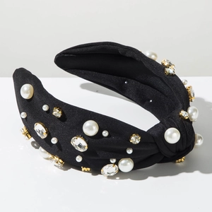 Gros plan d'un serre-tête noué en satin noir orné de perles blanches et de strass brillants