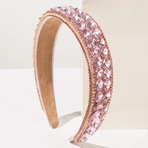Elegant Baroque headband with pink crystals and gold chain trim on a luxury stand
