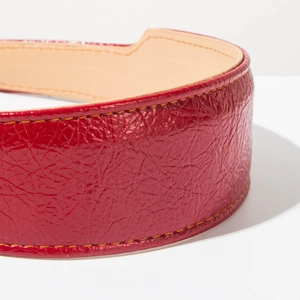 Vue macro d'un serre-tête en cuir verni rouge avec des coutures jaunes contrastantes