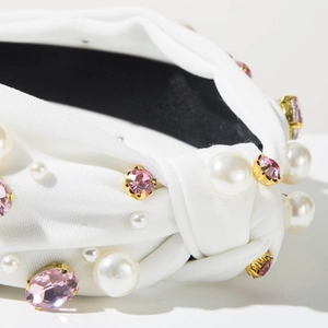 Détail du bandeau noué blanc avec pierres précieuses roses et perles décoratives