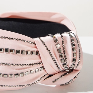 Macro view of light pink satin knotted headband with shiny dark grey rhinestones
