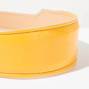 Détail du serre-tête en similicuir jaune plissé avec coutures fines et texture vernie