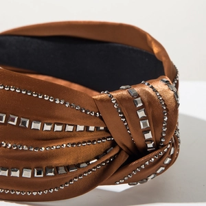 Close-up of brown satin knotted headband with shiny square and round rhinestones