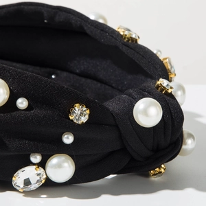 Détail du serre-tête en tissu noir noué orné de perles d'imitation et strass brillants
