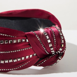 Detailed macro view of burgundy satin knotted headband with shiny square rhinestones