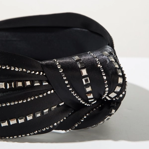 Macro shot of black satin headband featuring elegant silver rhinestones and knot design