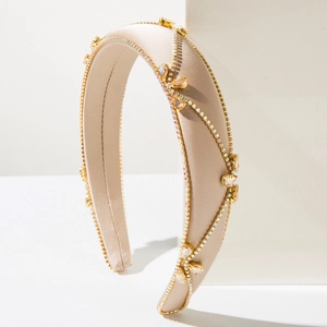 Close-up of champagne gold baroque headband with rhinestones and satin finish