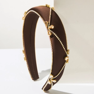 Detail of a brown satin headband with sparkling white diamonds and amber droplets