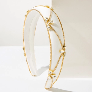 Detailed close-up of white satin headband with gold chains and inlaid clear crystals