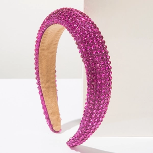 Détail d'un serre-tête rembourré rose fuchsia orné de strass brillants sur fond blanc