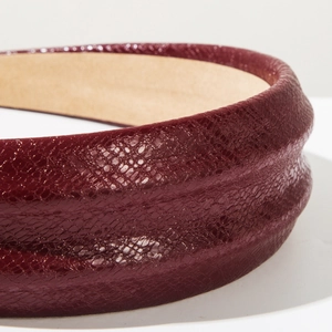 Macro shot of the wine red snakeskin embossed faux leather texture on this wide headband