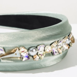 Détails d'un serre-tête en satin vert sauge orné de cristaux et perles de luxe